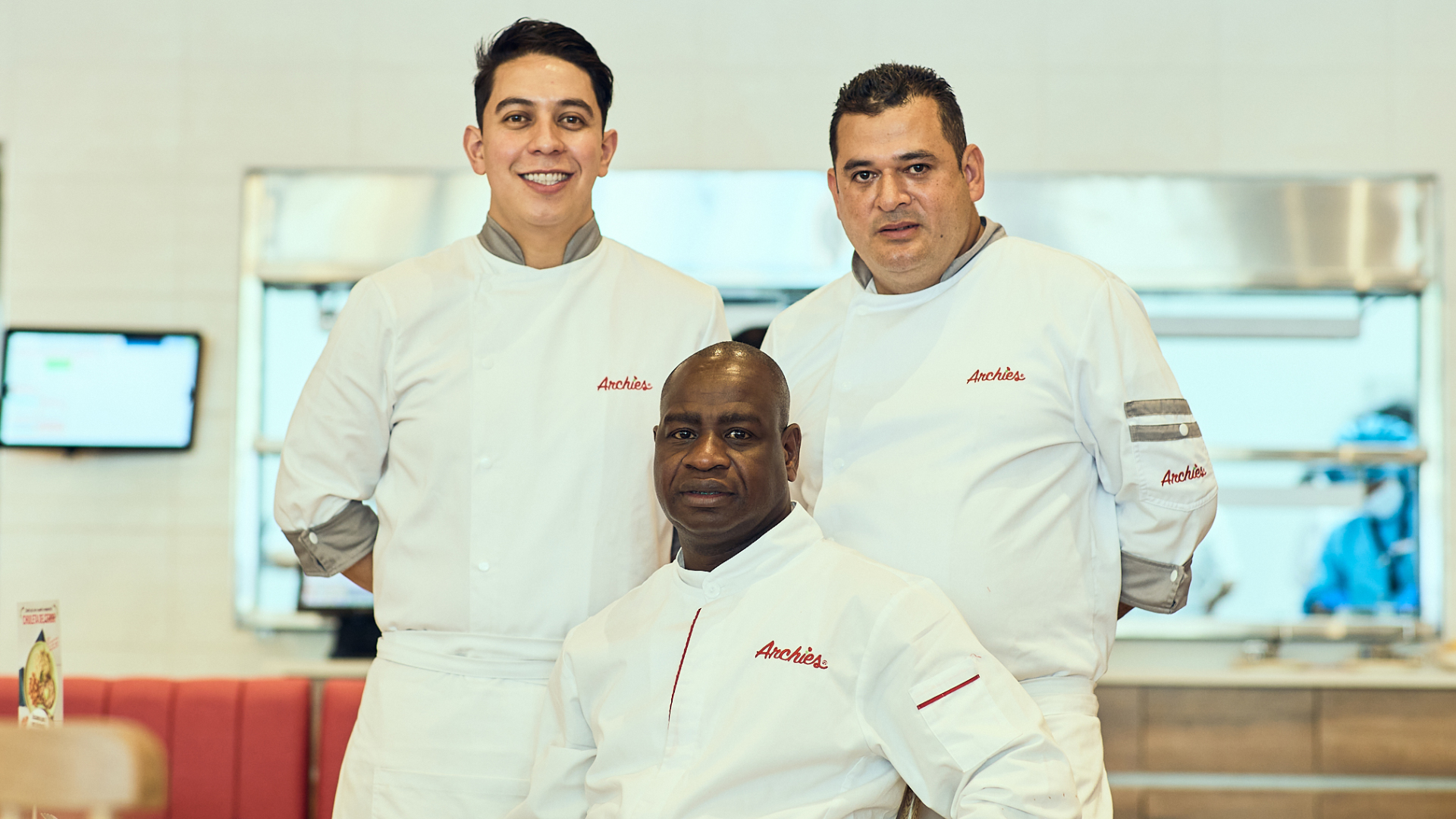 Three Archies chefs in white uniforms standing together in the kitchen