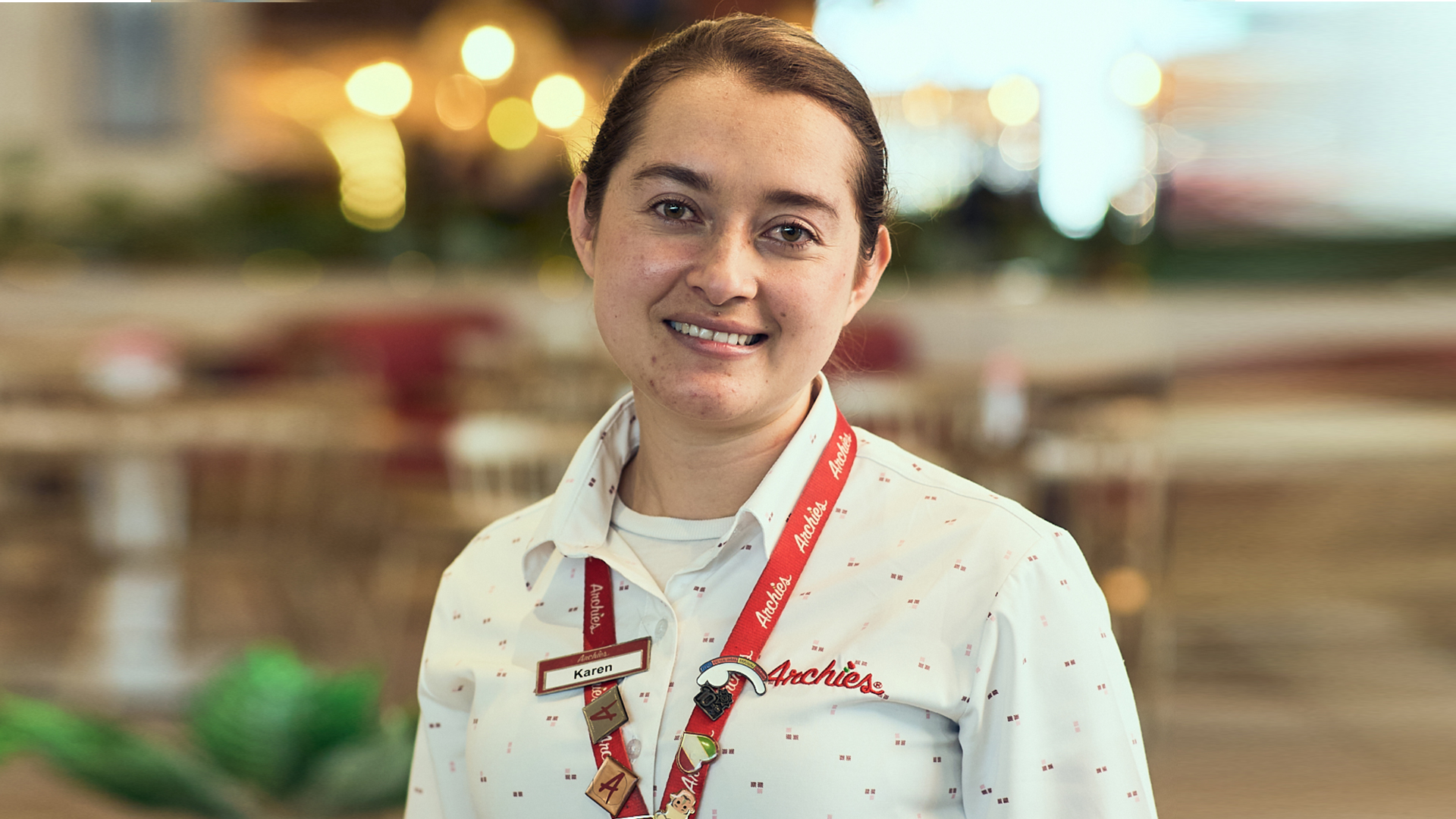 Smiling Archies employee wearing uniform with lanyard in restaurant setting